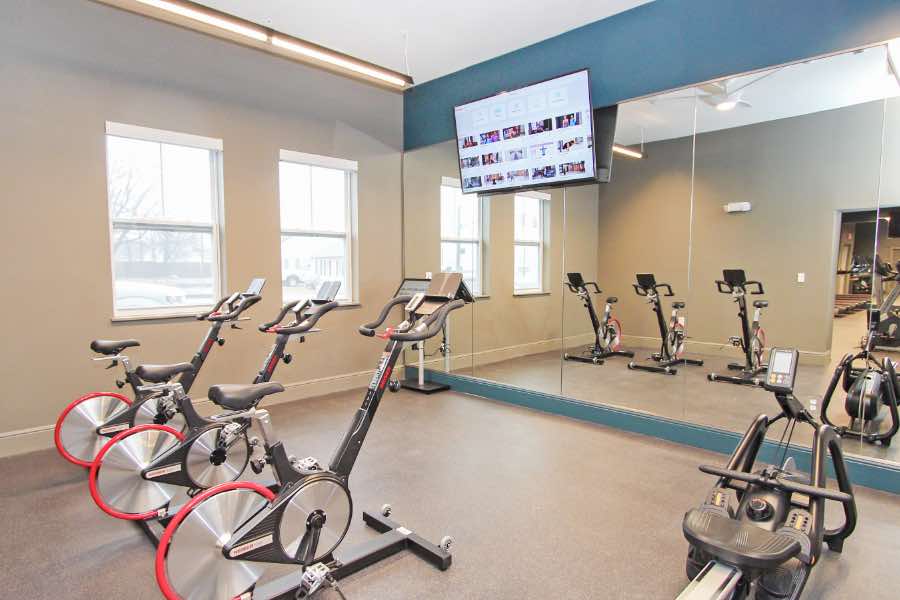 Finding the right amenities, like this well-equipped fitness center at Union Green Apartments, will help you decide on a community. Apartment community fitness center with exercise bikes, glass wall, and flat-screen TV.