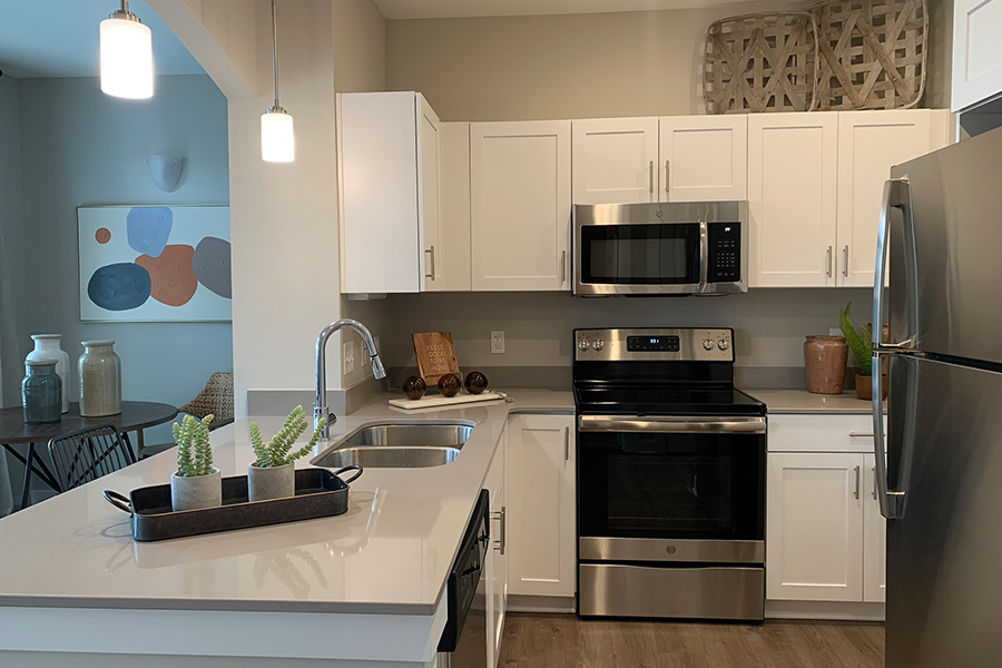 Embrace green living by cleaning kitchens with microfiber or dish towels instead of paper products. Kitchen at Harmony Apartments with white cabinets and stainless steel appliances.