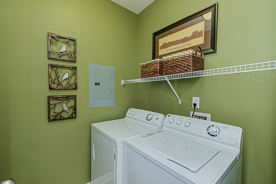 Baskets are perfect for adding organization and appeal when you have a laundry room like this one at Ivy Flats Apartments. Laundry room with washer, dryer, and storage baskets on wire shelf.