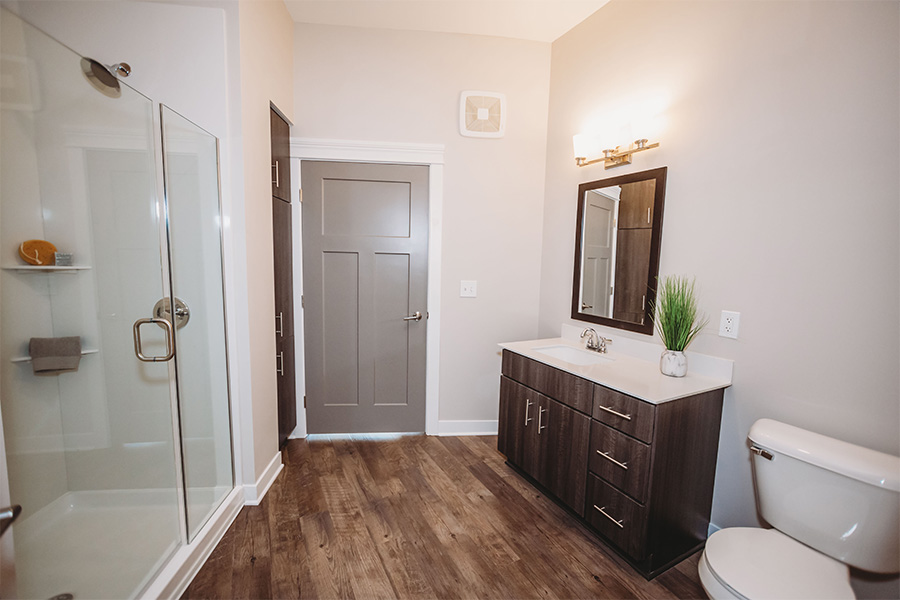A simple, uncluttered space like this bathroom at Penrose on Mass will help you relax. Apartment bathroom with vanity, wall mirror, and shower