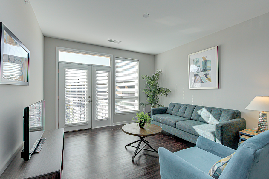 The furnishings in this living room at Riverview Apartments promote a functional space with plenty of room to move around. Living room at Riverview Apartments with sofa, chair, and TV stand.