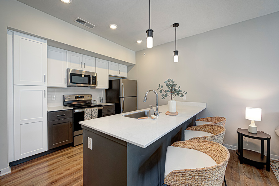 Put ideas for cutting electric bills into action when you rent a place like this at The Edge Apartments. Kitchen island with seating and overhead lights at an upscale apartment